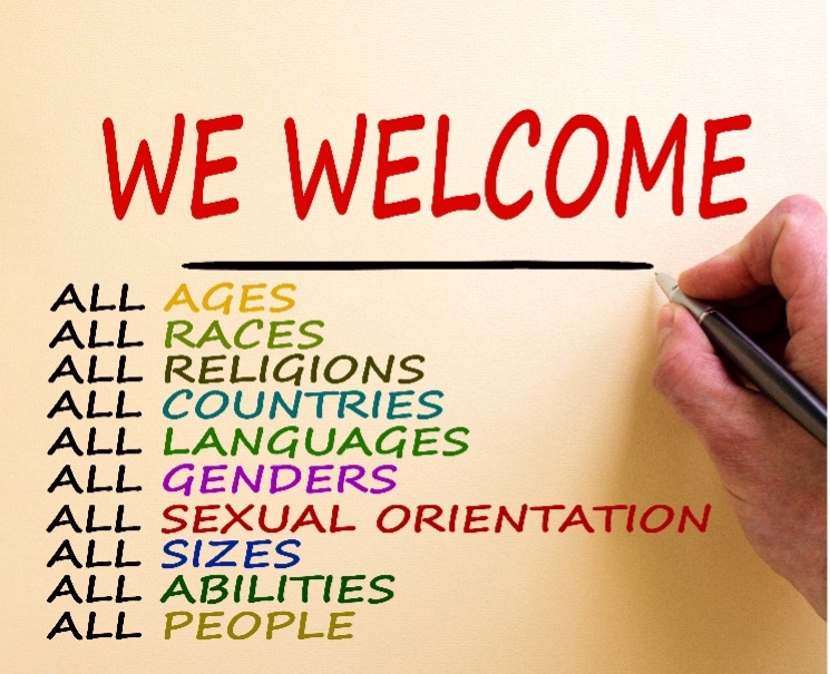 Image Description: A hand on the right holding a pen to write: “We welcome: all ages, all races, all religions, all countries, all languages, all genders, all sexual orientation, all sizes, all abilities, all people.