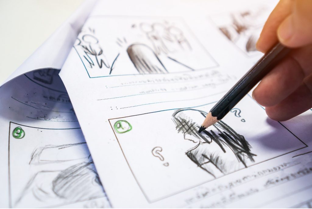 Image Description: A hand holds a pencil on the right side of a storyboard, hovering over a drawing of a person with question marks around their head. 