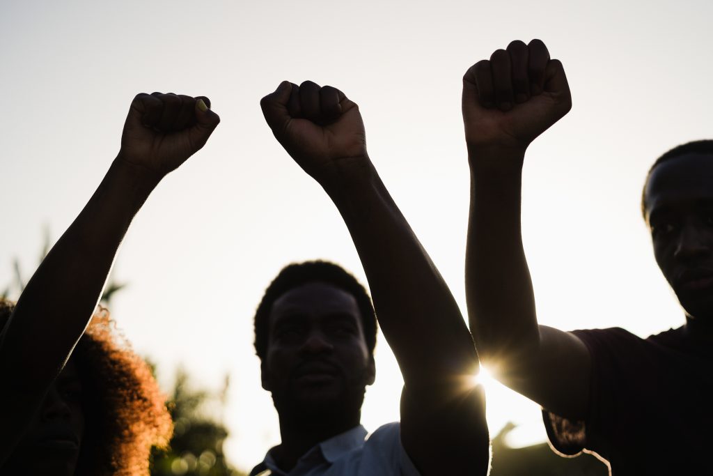 Image Description: Black demonstrator people holding hands against racism protest - Focus on fists
